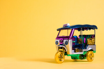 Model Toy tuk tuk isolated on yellow background. Thai traditional taxi in Bangkok Thailand....
