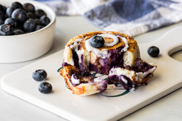 A freshly baked blueberry cinnamon roll on a platter, ready for eating.