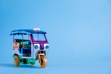 Model Toy tuk tuk isolated on blue background. Thai traditional taxi in Bangkok Thailand. Souvenir 