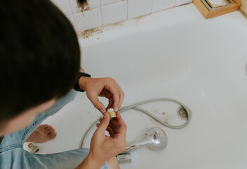 A young man wraps tow around the nut of a bathroom faucet.
