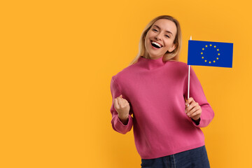 Happy young woman with flag of European Union on yellow background