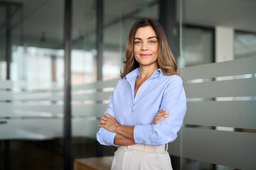 Confident smiling middle aged business woman attorney, 45 years old lady entrepreneur, mature female professional executive manager leader standing arms crossed in office looking at camera. Portrait.