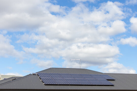 dark coloured corrugated tin roof with array of solar panels installed