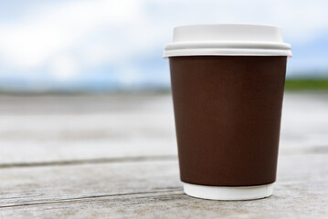 Paper coffee cup by a lake.