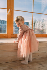 little cute girl in dress near window