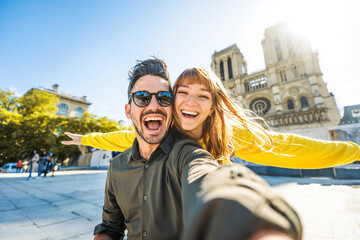 Happy couple of tourists visiting Notre Dame Cathedral in Paris, France - Boyfriend and girlfriend enjoying romantic vacation in Europe - Holidays and travel concept