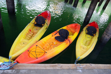 Three colorful kayaks at a dock under a pier