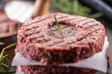 Fresh raw ground beef patties with rosemary salt and pepper made in a meat form on a cutting board - 789410760