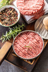 Fresh raw ground beef patties with rosemary salt and pepper made in a meat form on a cutting board - 789410981