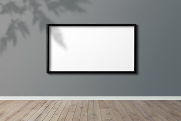 Black picture frame mockup hanging on a gray wall