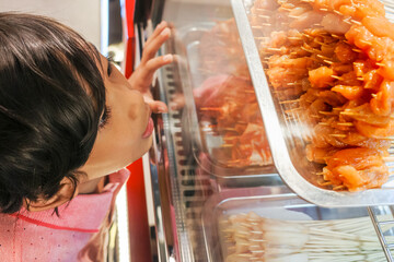 Asian little boy looking up on meal menu displayed at a local satay booth