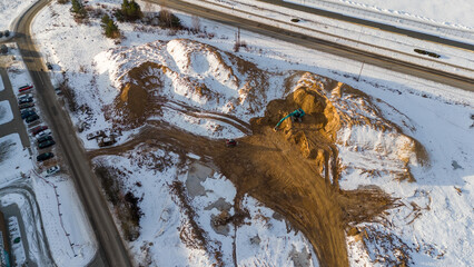 Drone photography construction site covered by snow and heavy equipment working during winter day