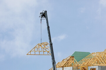 A crane lifting a pre fabricated roof truss onto a residential construction project
