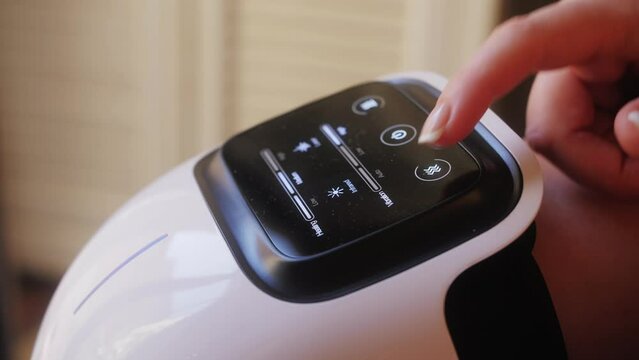 Woman uses portable electric massager for knees.