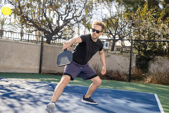 A man playing pickleball outside on a blue court. 
