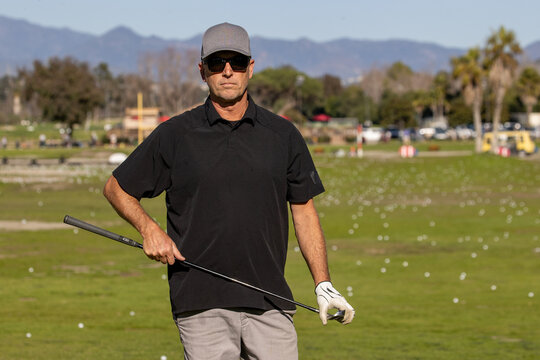 Man on the golf course. The golfer is holding a club at a driving range. 