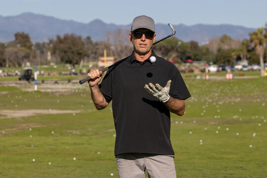 Man on the golf course. The golfer is holding a club at a driving range. 