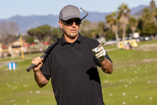 Man on the golf course. The golfer is holding a club at a driving range. 