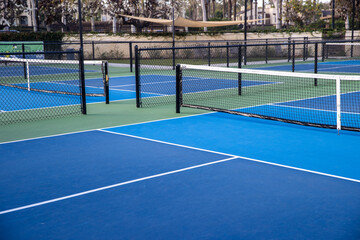 Empty pickleball court outside. The ground is blue and the net is mounted. 