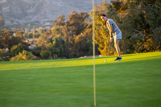 A woman lines up her putt on the green of a golf course. The popular sport requires skill, practice, and precision.