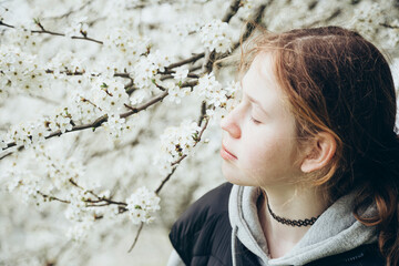 Portrait of young girl among spring flowering trees in the garden.