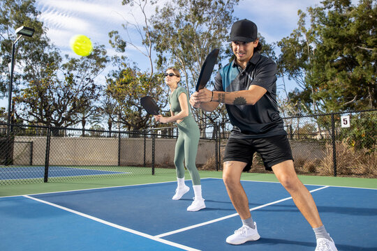Co-ed pickleball team. The players are active on the court for a fun and fast game. 
