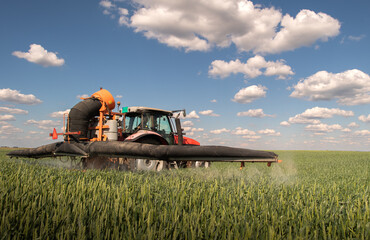 Tractor spraying pesticides wheat field. - 789417972