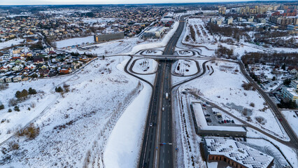 Drone photography of a high intensity street near city outskirts surrounded by buildings during winter morning - Powered by Adobe