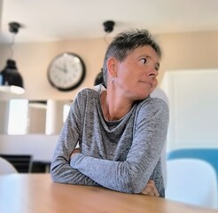 Woman with short gray hair, sitting with her arms folded, with her face turned backwards. Waiting...