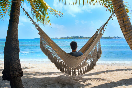 man tourist relaxing in beach hammock, vacation travel to tropical island