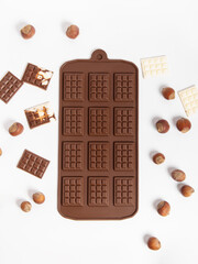 Silicone mold for chocolate on white background. Making chocolate. Small chocolates and hazelnuts. Top view