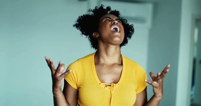 One frustrated young black woman screaming in despair at sky gesturing with hands body feeling distraught and overhwelmed by problems, 20s person wanting to give up