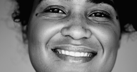 Monochrome portrait of a joyful black woman macro close-up face expressing happiness. One latina...