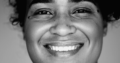 Monochrome portrait of a joyful black woman macro close-up face expressing happiness. One latina...