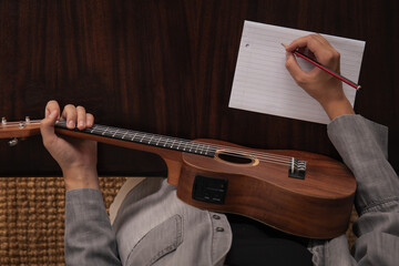 Girl with a ukulele. The girl writes a song on a piece of paper. A girl composes a song and plays...