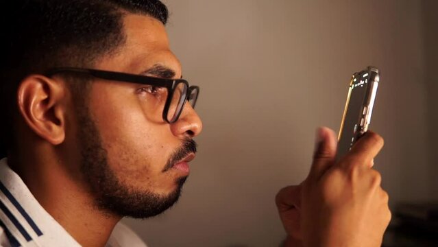 Side view portrait of young man wearing a eye glasses and holding a phone. addiction of phone concept.