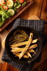 Roasted chicken breast cut into strips, roasted in a cast iron skillet accompanied by roasted nopales and fresh salad, served on a rustic wooden table. Simple and nutritious homemade recipe. - 789438508