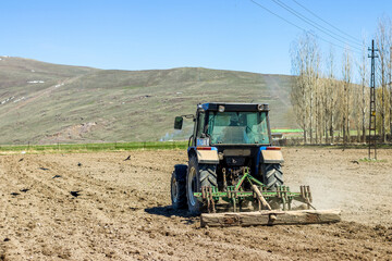 A farmer tilling the soil in spring with a tractor, prepping for a new season of growth. This image...