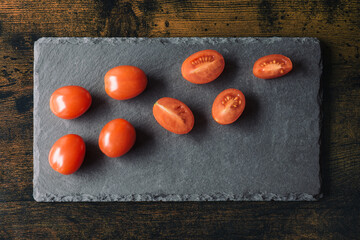 Fresh cherry tomatoes displayed on a slate cutting board, set on a wooden table. Perfect natural...