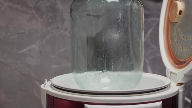 Steam fills a glass jar in a sterilizer.