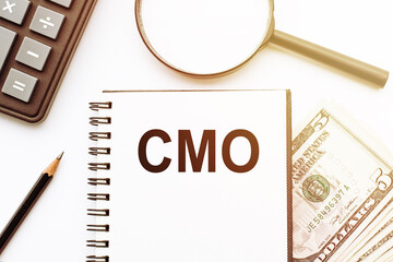 White notepad with the text of the CMO on the background of dollars and office tools.