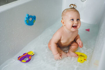 A little boy of 6 months with a ponytail on his hair is bathing in the bathroom. Bathing a baby....