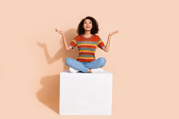 Full body photo of satisfied girl wear t-shirt sit on platform look empty space palm hold objects isolated on pastel color background