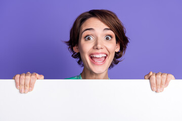 Photo portrait of attractive young woman behind white empty space excited dressed stylish green clothes isolated on violet color background © deagreez