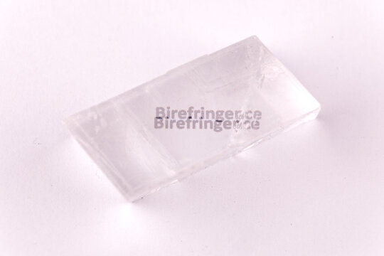 Optical birefringence demonstrated using a text using a natural double spar / calcite crystal