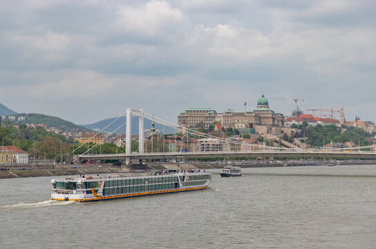 Budapest, Hungary - April 24, 2023: A picture of the Elisabeth Bridge and the Buda Castle at the far right, while a tour boat sails in the Danube.