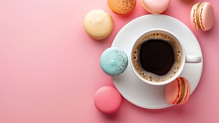 Cup of coffee and colorful macaron on pastel pink background top view