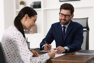 Woman signing document in lawyer's office, selective focus