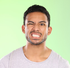 Man, portrait and angry face with disgust for awkward humor or funny humor on a green studio background. Frustrated male person or joker with goofy expression, attitude or upset behavior in anger