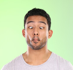 Man, play and silly in studio, face and goofy comic or funny expression on green background. Male person, mockup space and guy for joke or comedy, student and humor for crazy character and quirky